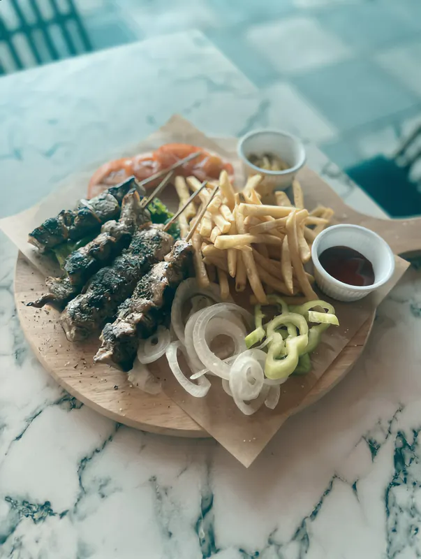Souvlaki platter with fries, peppers, onions and dips