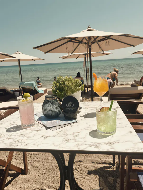 Drinks on a marble table under a parasol, with the beach beyond